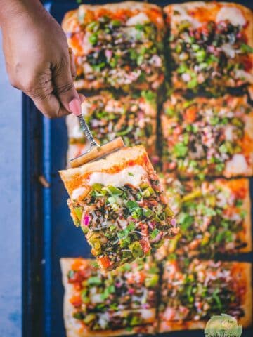 a hand holding a slice of Easy Tomato Bruschetta Pizza.