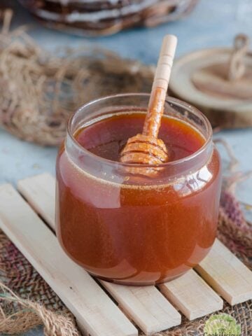 Homemade vegan honey stored in a glass jar with a dipper in it.