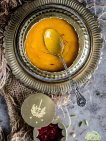 Aamras served in a brass bowl and spoon in it.