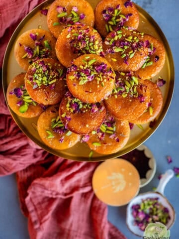 Gulab Jamun Cupcakes topped with pistachios and rose petals served in a plate.